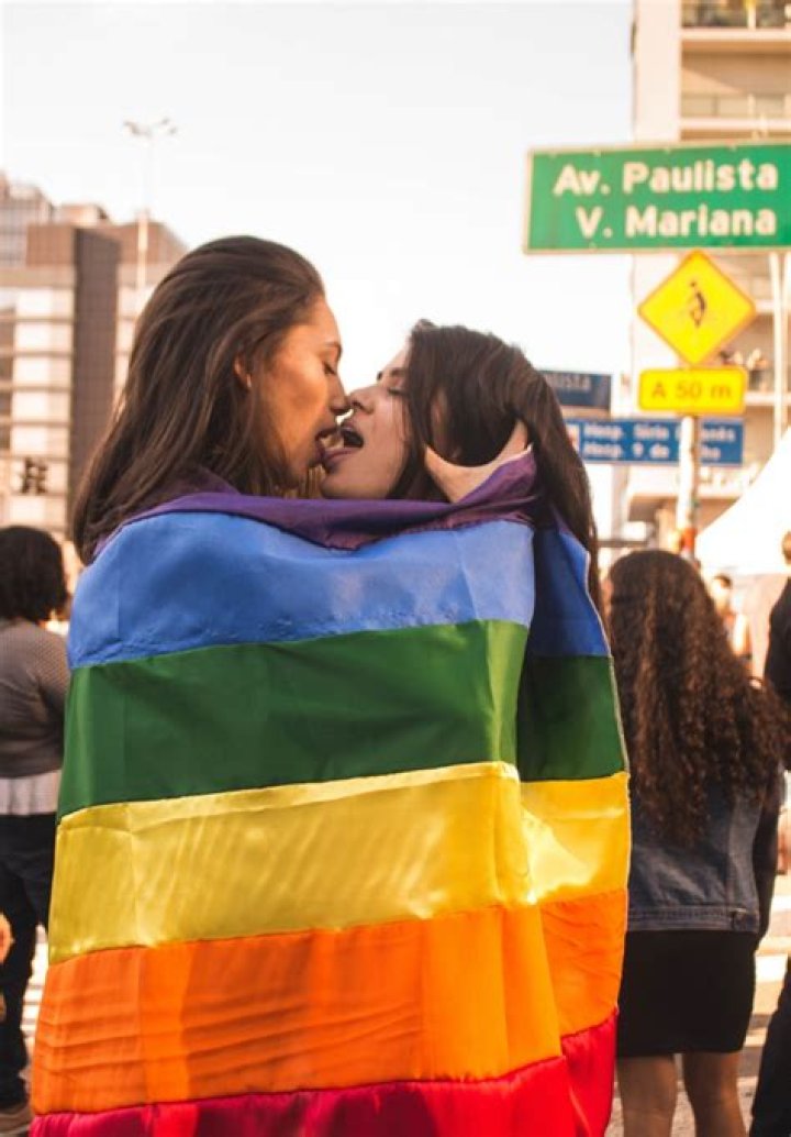 Two Women Kissing While Wrapped in Rainbow Flag · Free Stock Photo